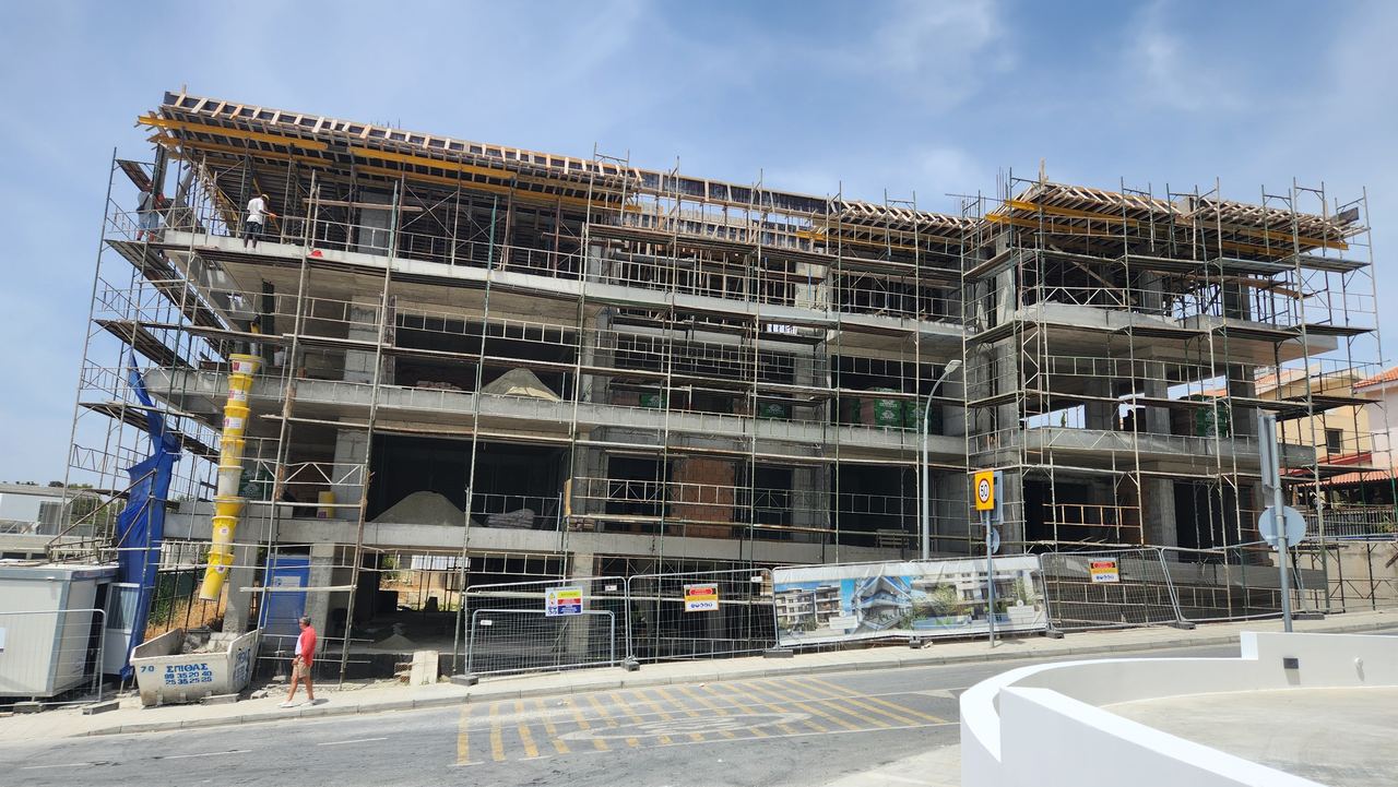 Multi-storey residential building under construction, with scaffolding and formwork on the concrete frame